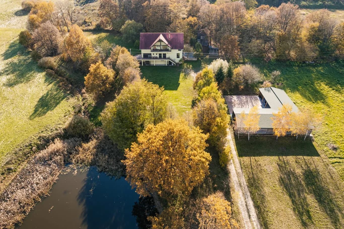 Vedere aeriană a domeniului HOP Events toamna — casa de oaspeți, hambarul, lacul și pădurea din jur