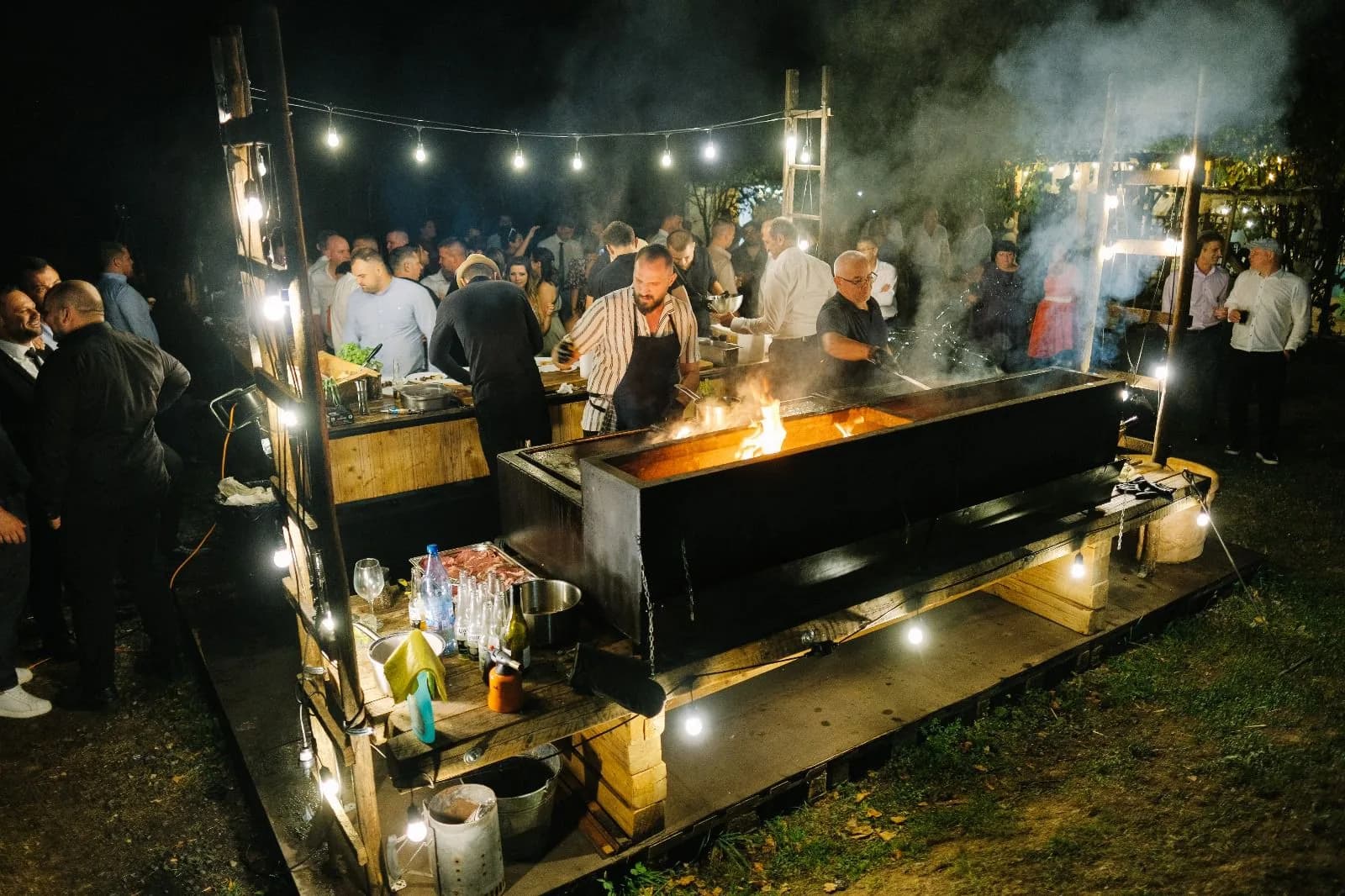 Stație de gătit la foc deschis, invitați privind în jurul flăcărilor